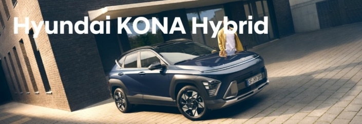 Hyundai KONA Hybrid steht vor Gebäude, Person steht daneben
